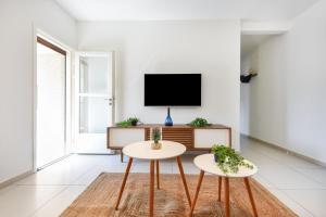 uma sala de estar com duas mesas e uma televisão em Lily of the Valley by HolyGuest em Tel Aviv