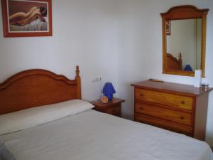 sypialnia z łóżkiem, komodą i lustrem w obiekcie Apartamento Amatista Calpe w mieście Calpe