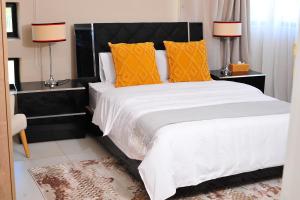 - une chambre avec un grand lit et des oreillers orange dans l'établissement Square Connexions Guest House, à Gaborone