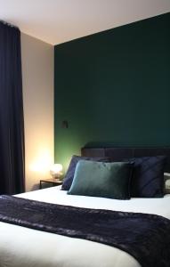ein Schlafzimmer mit einem großen Bett und einer grünen Wand in der Unterkunft Résidence "Le Vélodrome" in Maubeuge