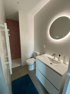 een badkamer met een wastafel, een toilet en een spiegel bij Relais de la Joselière in Pornic