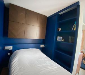 een blauwe slaapkamer met een wit bed en planken bij Relais de la Joselière in Pornic