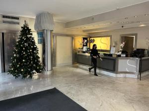 Eine Frau, die in einer Hotellobby mit einem Weihnachtsbaum spazieren geht in der Unterkunft Hotel Sporting Brugherio in Brugherio