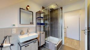 a bathroom with a sink and a shower with a mirror at Apartmenthaus Celik in Bielefeld
