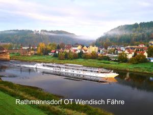 ein Boot, das einen Fluss hinunter in der Nähe einer Stadt fährt in der Unterkunft Ferienwohnung Füssel in Rathmannsdorf