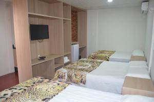 a hotel room with three beds and a flat screen tv at Pousada Encantos da Amazônia in Alter do Chao