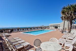 una piscina con tumbonas, una mesa y un montón de sillas en Ramsgate Harbor 26 en Panama City Beach