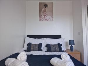 a bedroom with a bed with two white chairs at The Commuter's Lodge in Laindon