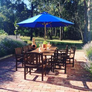 una mesa de madera y sillas con una sombrilla azul en The Retreat at Amryhouse, en Ashbourne