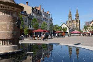 a city square with a reflection of a fountain at Joli studio avec parking privé in Moulins