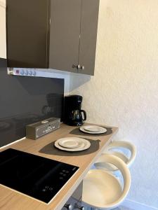 a kitchen counter with three white plates on a table at Joli studio avec parking privé in Moulins