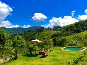 two chairs and an umbrella next to a swimming pool at Rancho do Paioleiro in São Bento do Sapucaí
