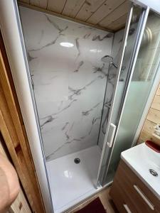 a bathroom with a shower with white marble at Les Mini-Chaumières in Saint-Martin-Saint-Firmin