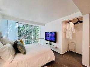 1 dormitorio con 1 cama, TV y ventana en Loft de estilo, moderno, amplio y súper cómodo., en Ciudad de México