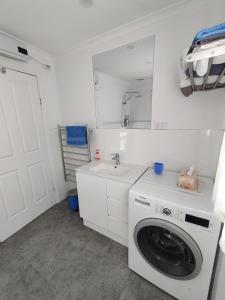 een witte wasruimte met een wasmachine en een wastafel bij Walnut Cottage via Leongatha in Leongatha