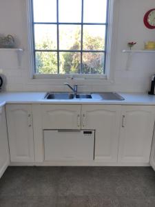 a white kitchen with a sink and a window at Walnut Cottage via Leongatha in Leongatha