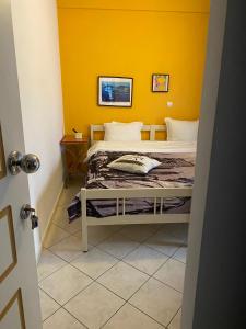 a bedroom with a bed with a yellow wall at Maria's rooms CHANTZARA SPYROPOULOS Flats to Let-City Center in Igoumenitsa