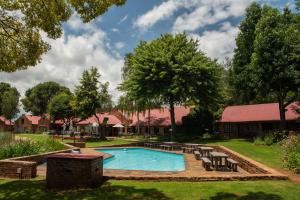 a swimming pool in a yard with chairs around it at Critchley Hackle - Managers Cottage in Dullstroom