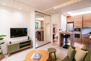 een woonkamer met een bank en een tv en een keuken bij AlMar- Διαμέρισμα στο κέντρο της Ηλιούπολης in Athene