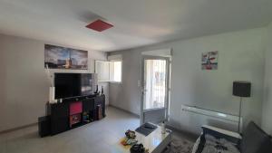 a living room with a flat screen tv and a table at Maison duplex de ville avec terrasse et clim in Foucherans