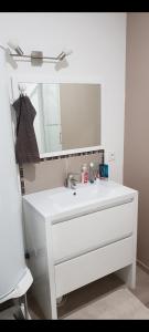 ein Badezimmer mit einem weißen Waschbecken und einem Spiegel in der Unterkunft Maison de ville avec terrasse et clim in Foucherans