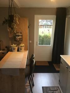 uma cozinha com uma mesa de madeira e uma porta em Vakantiehuisje B&B de Kleine Voskuil em Hulshorst