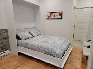 a bedroom with a bed in a white room at Loft 102 au cœur de Rimouski près du St-Laurent in Rimouski