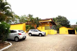 two cars parked in front of a yellow building at Fazenda Alto Alegre Pousada in Bonito