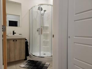 a white bathroom with a shower and a sink at Loft 102 au cœur de Rimouski près du St-Laurent in Rimouski