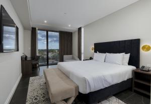 um quarto com uma cama grande e uma janela grande em Crowne Plaza Sydney Burwood, an IHG Hotel em Sidney