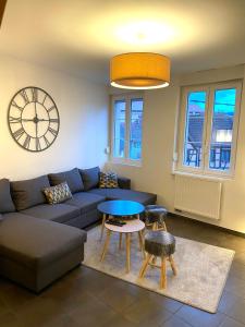 sala de estar con sofá, mesa y reloj en Duplex moderne à 10 minutes de Colmar, en Wintzenheim