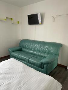um sofá de couro verde num quarto com uma televisão em Séjour confortable et agréable pour la famille... em Étampes