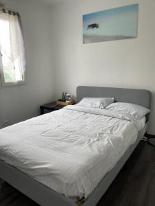 uma cama branca num quarto com uma fotografia na parede em Séjour confortable et agréable pour la famille... em Étampes