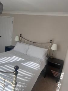 um quarto com uma cama com lençóis brancos e 2 candeeiros em Two-bedroom Apartment em Yeovil