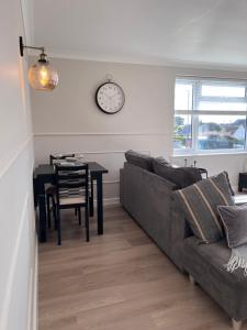a living room with a couch and a table with a clock at Two-bedroom Apartment in Yeovil