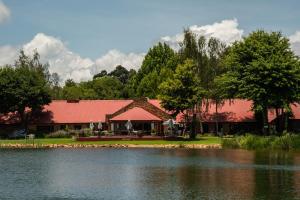 a building with a red roof next to a lake at Critchley Hackle - Managers Cottage in Dullstroom