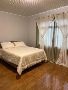 a bedroom with a bed and a window with curtains at Lar Serra Gaúcha in Canela