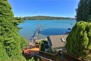 a house on the shore of a lake with a dock at Seascape Suite by IRIS PROPERTIES! in Sooke