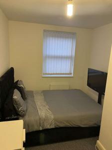 a bedroom with a bed and a window and a television at Modern Huddersfield apartment in Huddersfield