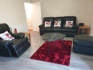 a living room with a black leather couch and a table at Mesa property services in Grays Thurrock