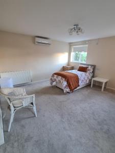 um quarto com uma cama, uma cadeira e uma janela em Mesa property services em Grays Thurrock