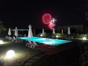 uno spettacolo pirotecnico nel cielo sopra una piscina di notte di Tenuta Pigliano Hotel a Bagnolo del Salento