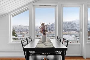 a dining room with a table and chairs and windows at View of Tromsø in Tromsø