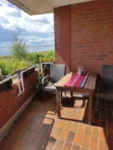 eine Terrasse mit einem Holztisch und Stühlen an einer Ziegelwand in der Unterkunft Schönes Feriendomizil mit Meerblick Südstrand Nähe Fliegerdeich in Wilhelmshaven in Wilhelmshaven