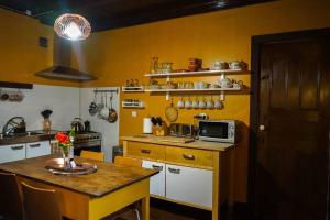 a kitchen with yellow walls and a table with a microwave at Casa Via d'Agua in Fajã Grande in Faja Grande
