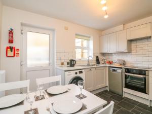 una cucina con tavolo e sedie e una cucina con piano cottura di Maisy Cottage a Weymouth
