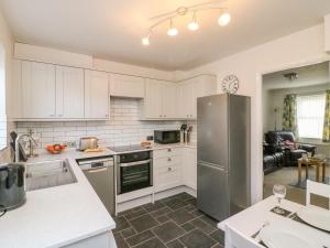 una cucina con armadi bianchi e frigorifero in acciaio inossidabile di Maisy Cottage a Weymouth