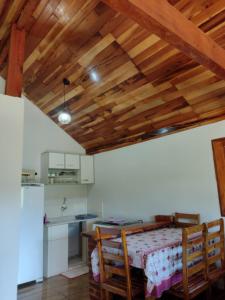 a kitchen with a table and wooden ceilings at Chalés Encantos de Minas in Bueno Brandão