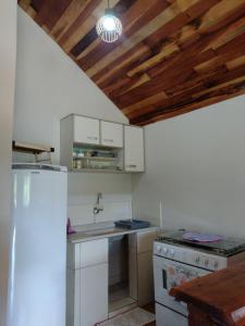 cocina con electrodomésticos blancos y techo de madera en Chalés Encantos de Minas en Bueno Brandão