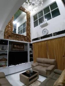 ein Wohnzimmer mit einem Sofa und einer Uhr an der Wand in der Unterkunft TITE homestay. Staycation feels @home in Salakan